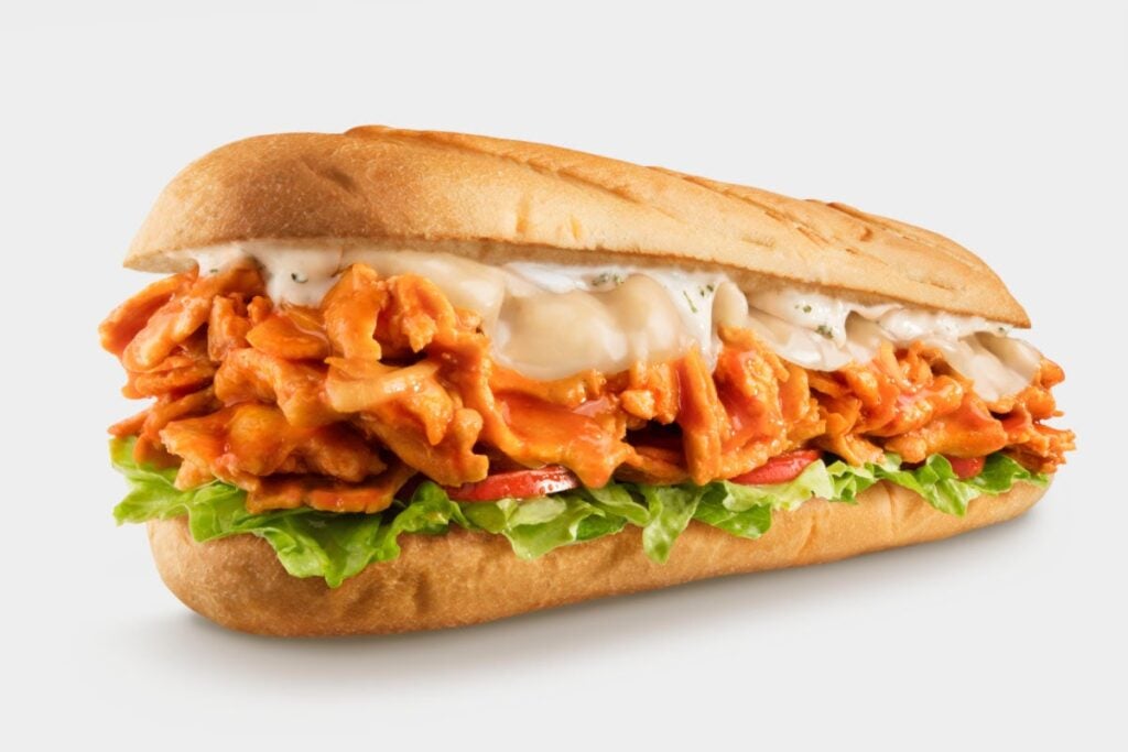 This is a buffalo cheese steak made with grilled chicken, buffalo sauce, and ranch dressing with onions and banana peppers, topped with provolone on a roll