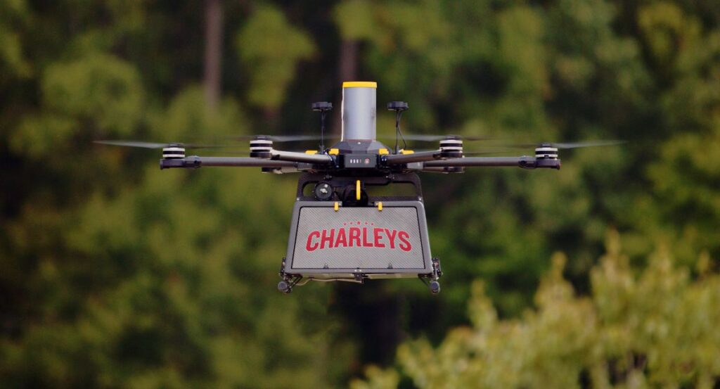 A Flytrex delivery done with the Charleys logo in red flying near trees in Durham, North Carolina.